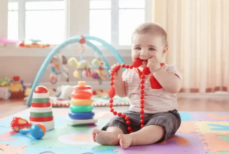 a baby teething on beads