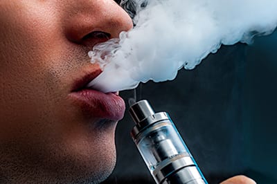 A young person vaping using an e-cigarette device.