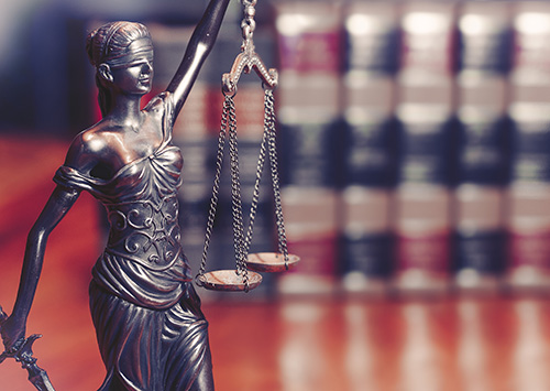 a figure of lady justice on a desk by books