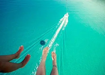 An aerial view showing two pairs of feet - belong to people parasailing - dangling hundreds of feet above the water.