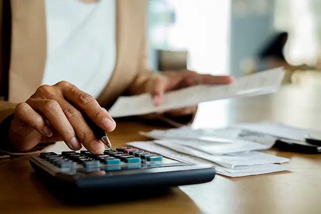 A woman with a calculator paying bills