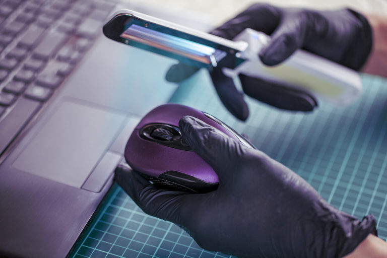 An ultraviolet wand being used to sanitize a computer mouse