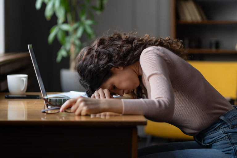 An exhausted lawyer rests her head on her laptop
