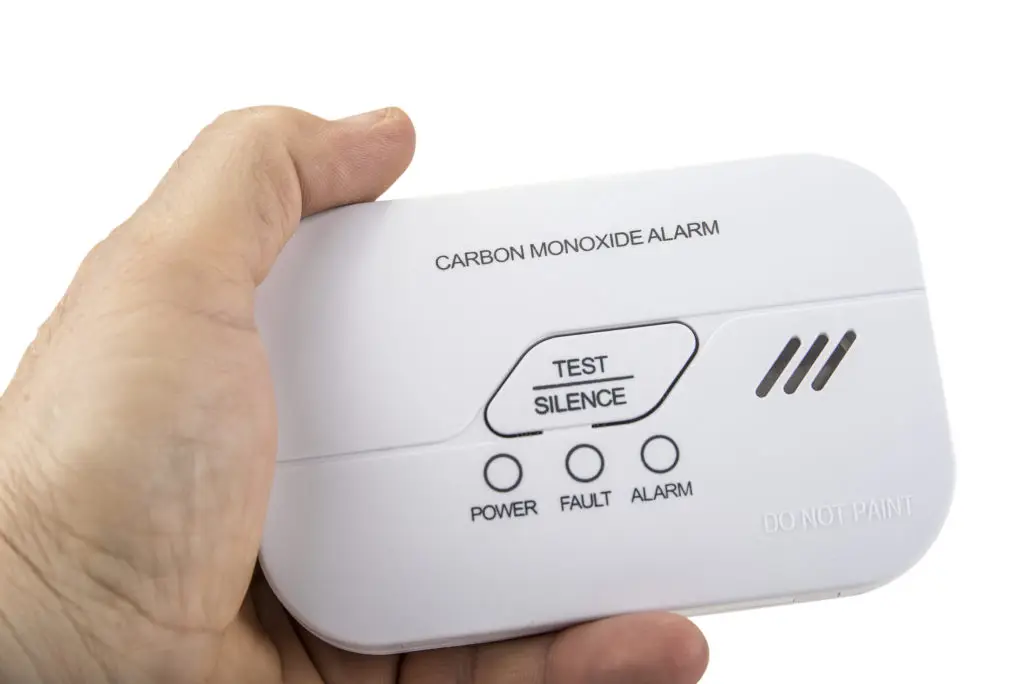 A hand holding a carbon monoxide alarm