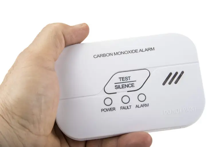 A hand holding a carbon monoxide alarm
