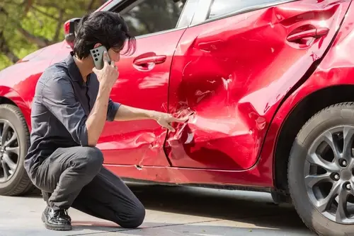 Damaged car with crumpled hood after roadway collision and insurance claim concept
