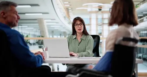 Injured worker holding shoulder while meeting with lawyer across office desk