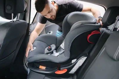Car seat defect injury lawyer Man installing a child seat in a car